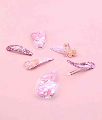 Set of colorful hair clips on a pink background