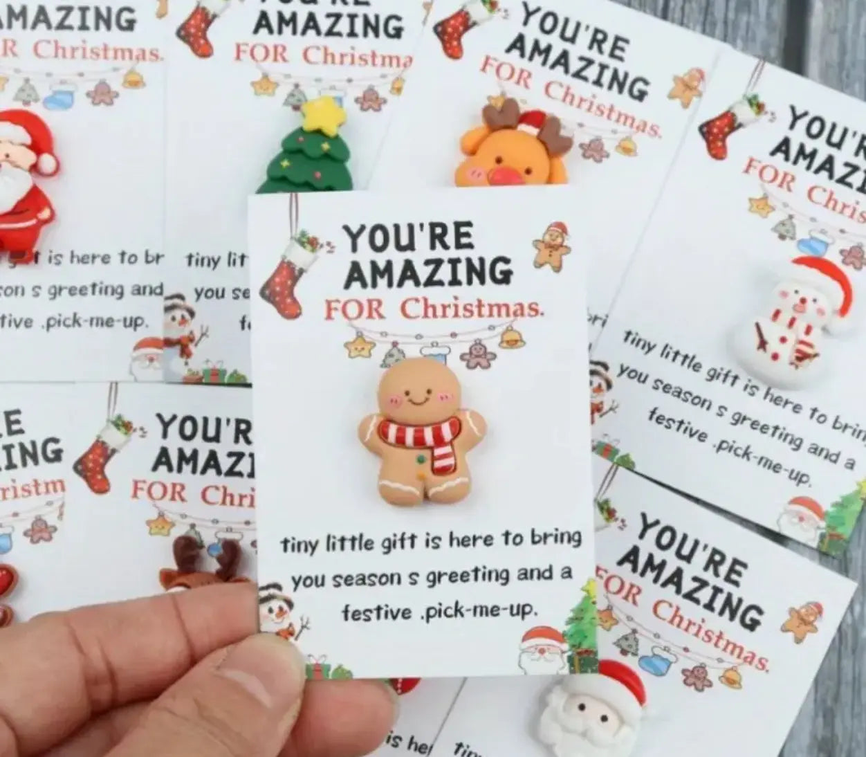Cards with Christmas-themed designs and text 'You're Amazing for Christmas' held by a hand.