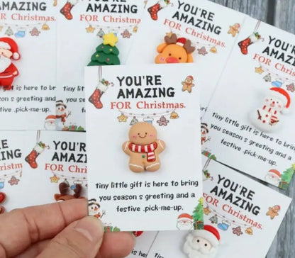 Cards with Christmas-themed designs and text 'You're Amazing for Christmas' held by a hand.