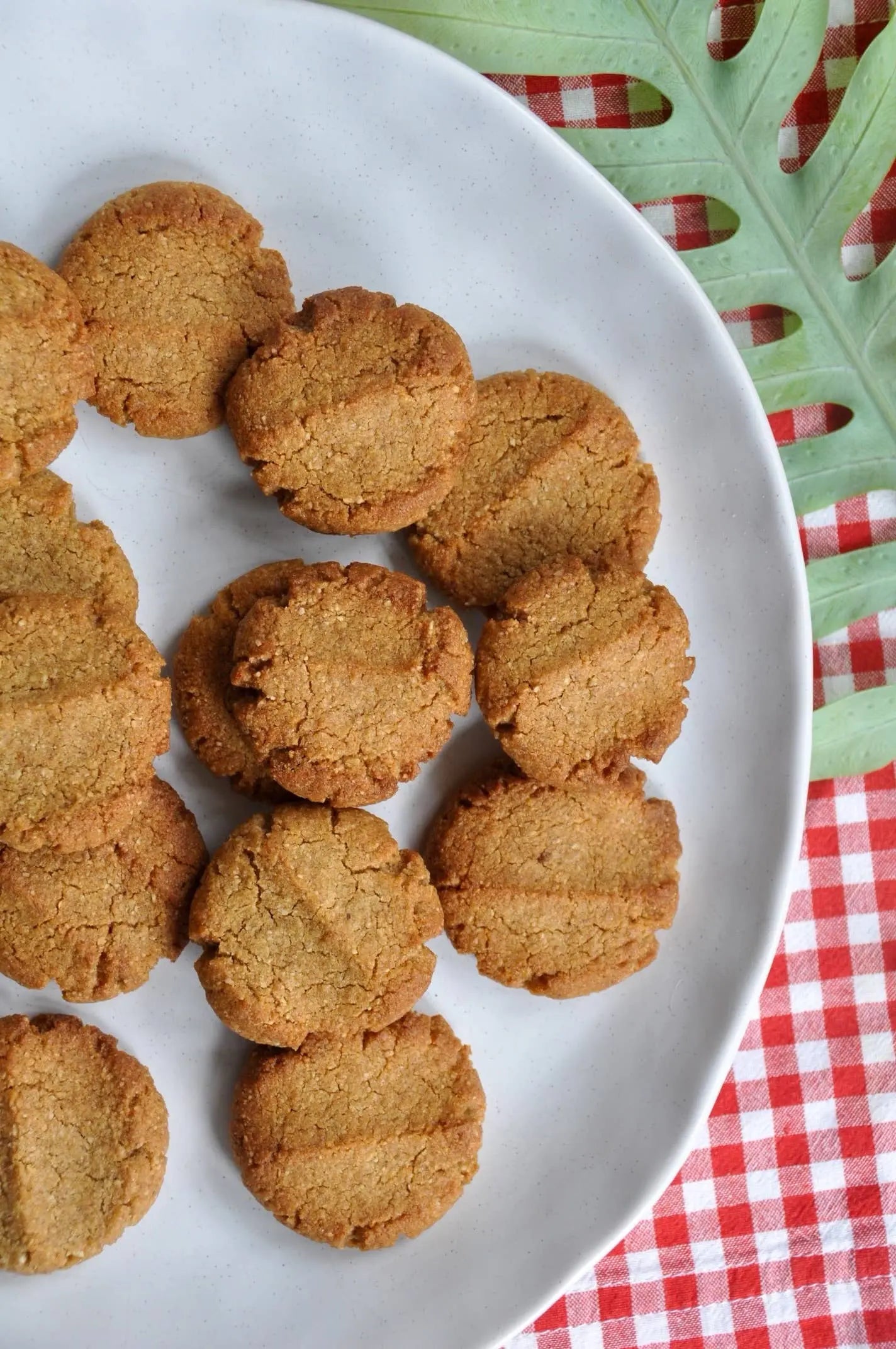 Round cookies on a white plate with a red and green checkered tablecloth in the background