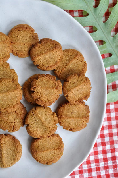 Round cookies on a white plate with a red and green checkered tablecloth in the background