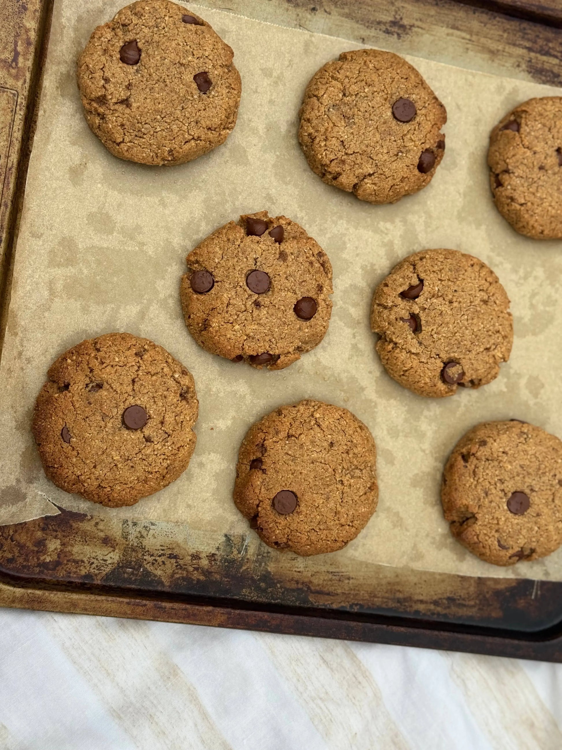 Chocolate chip cookies on a baking tray with a marble countertop
